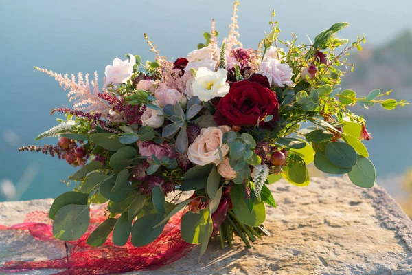 Nádherné svatební kytice stojí na kámen v paprscích zapadajícího slunce — Stock fotografie