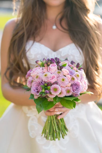 Невеста держит в руках розовый свадебный букет из разных цветов — стоковое фото