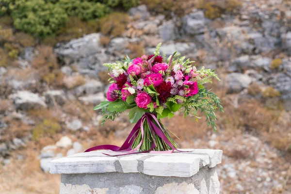 Buquê de casamento vermelho brilhante fica em um pedestal de pedra — Fotografia de Stock