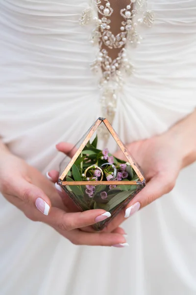 Meisje met een kleine florarium met groen en trouwringen binnen, close-up — Stockfoto