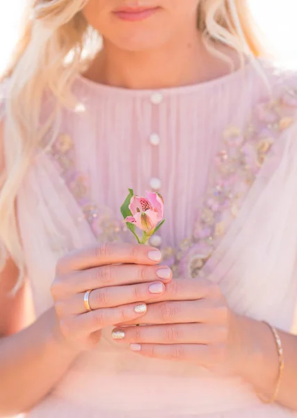 Vrouw in roze jurk bedrijf alstroemeria bloem — Stockfoto