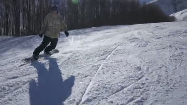 Snowboarder genieten van een berg rijden in een skiresort op een zonnige dag — Stockvideo
