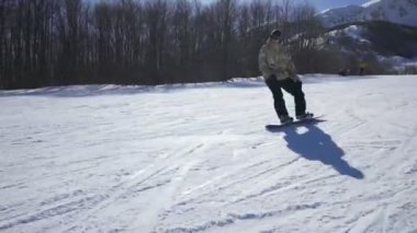 güneşli bir günde bir kayak merkezi bir dağ zevk snowboard binmek