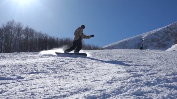 Snowboardåkare bromsar genom att lyfta en snöfontän i luften — Stockvideo