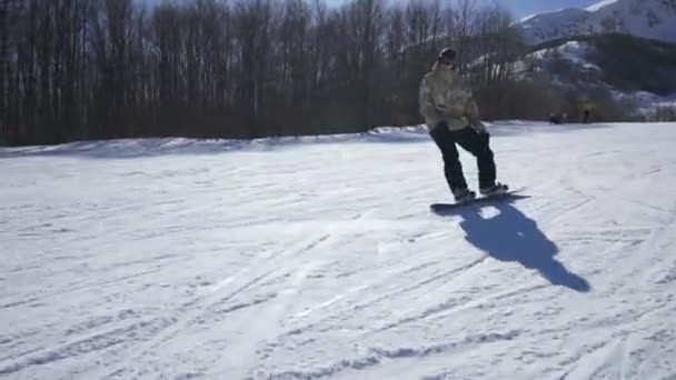 Сноубордист наслаждается горной прогулкой на горнолыжном курорте в солнечный день — стоковое видео