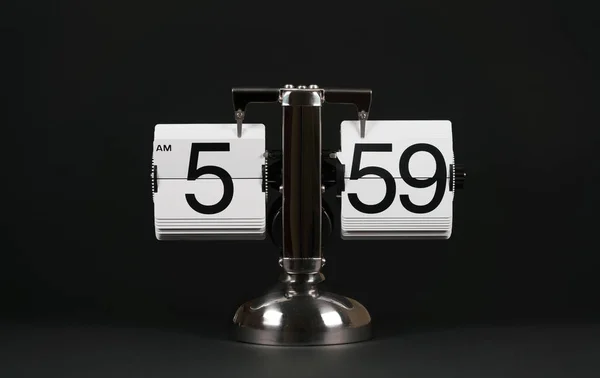 Isolated vintage flip clock on black background at five oclock and fifty nine minutes