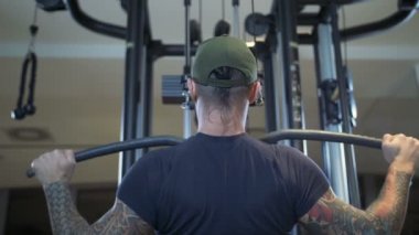 adam spor salonunda latissimus dorsi lat pulldown makine tarafından eğitiyor.