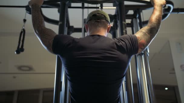 Человек в тренажерном зале тренирует latissimus dorsi на машине Lat pulldown — стоковое видео