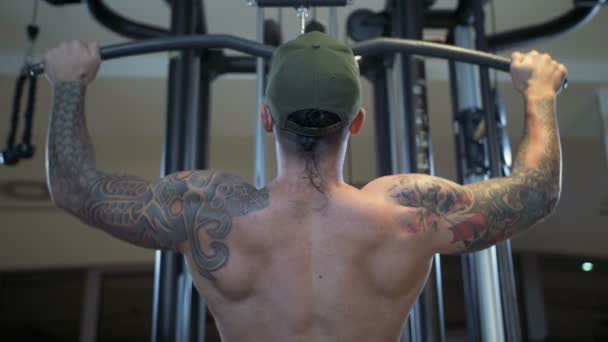 Человек в тренажерном зале тренирует latissimus dorsi на машине Lat pulldown — стоковое видео