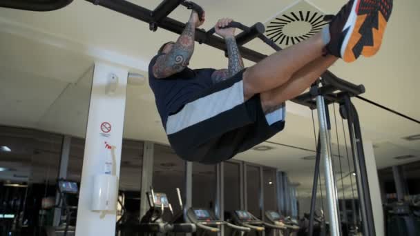 Adam yukarı çekerek bacaklar yatay olarak tutan bir spor salonunda — Stok video