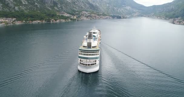 Kotor, Montenegro - 15 de mayo de 2019: Vista aérea de un crucero mediano de lujo navegando hacia el puerto a través de la bahía — Vídeo de stock