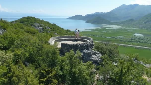 La coppia si abbraccia e gode di una magnifica vista dal ponte di osservazione del lago di Skadar — Video Stock