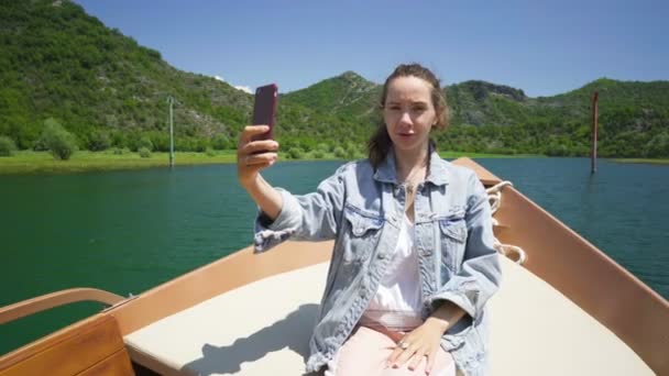 Молодая женщина садится в катер и делает видеозвонок — стоковое видео