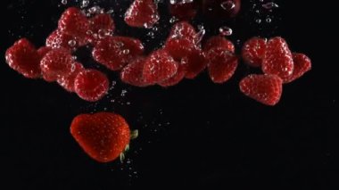 olgun meyveleri karışımı siyah bir arka plan üzerinde suya düşüyor