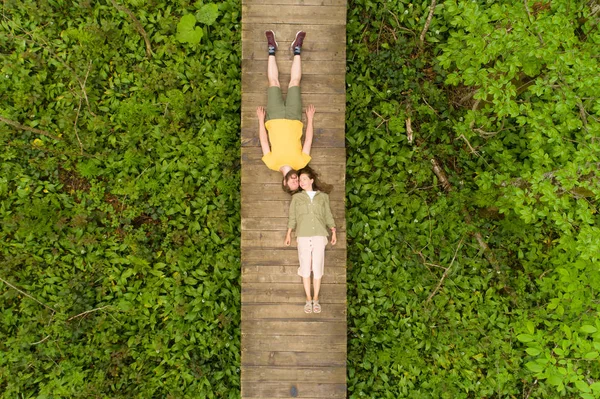 Coppia di innamorati sdraiati su un ponte di legno nel bosco — Foto Stock