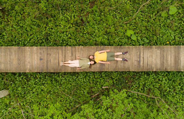 couple of lovers lying on a wooden bridge in the forest