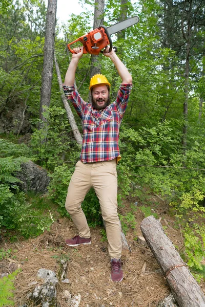 Skäggiga Lumberjack med en motorsåg gör ansikten — Stockfoto