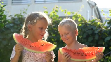 bahçede karpuz yiyen erkek ve kız kardeş