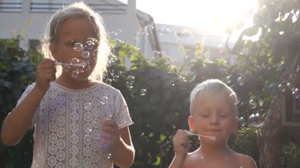 Hermano y hermana soplar burbujas en el jardín — Vídeo de stock