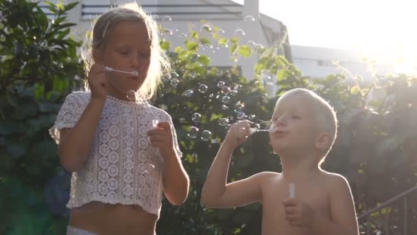 Broer en zus blazen bubbels in de tuin — Stockvideo