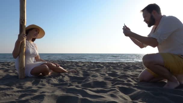Man photographs his girlfriend on the beach — Stock Video