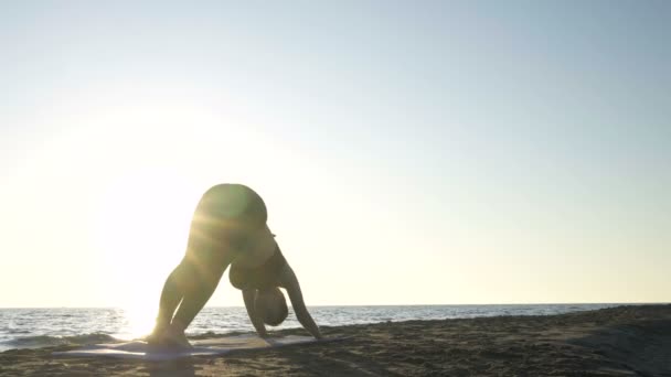 Junge kaukasische Frau praktiziert Yoga am Strand in der Nähe der ruhigen See. — Stockvideo