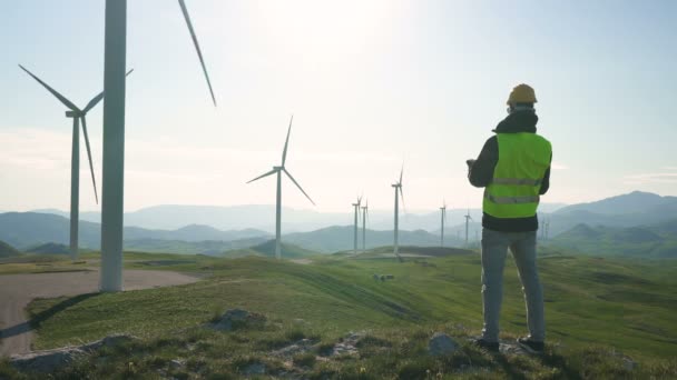 Technicus Engineer in Wind Turbine Power Generator Station staat met een tablet in zijn handen — Stockvideo