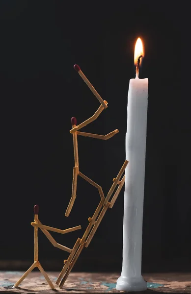 Matchsticks in form of a man lighting a candle, matchstick man lighting a candle.