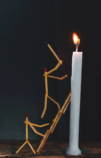 Matchsticks in form of a man lighting a candle, matchstick man lighting a candle.