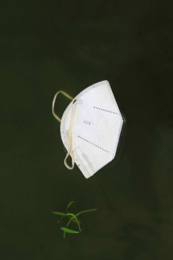 Denize atılan cerrahi maske. Okyanus kirliliği ve Coronavirus (Covid-19) salgını sırasında cerrahi maskelerin aşırı kullanımının sonuçları.