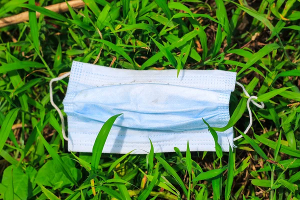 Cerrahi maske, çimenlere atılan cerrahi maske, çevre kirliliği ve Coronavirus (Covid-19) salgını sırasında cerrahi maskelerin aşırı kullanımının sonuçları..