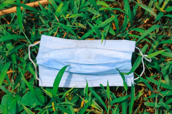 Cerrahi maske, çimenlere atılan cerrahi maske, çevre kirliliği ve Coronavirus (Covid-19) salgını sırasında cerrahi maskelerin aşırı kullanımının sonuçları..