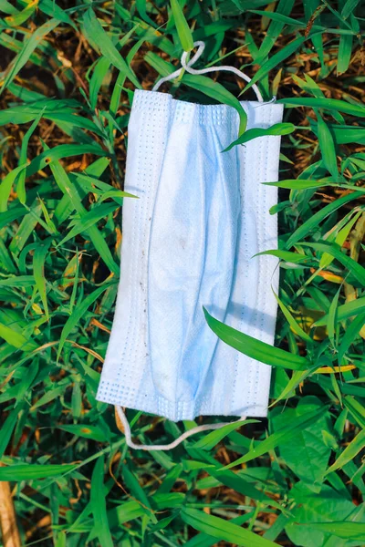 Cerrahi maske, çimenlere atılan cerrahi maske, çevre kirliliği ve Coronavirus (Covid-19) salgını sırasında cerrahi maskelerin aşırı kullanımının sonuçları..