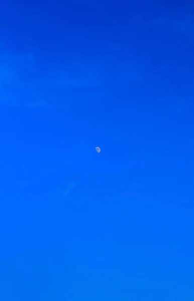 Half-moon with blue sky. The majestic moon, clear sky.