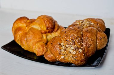 Mısır gevreği ve tereyağı kruvasan siyah tepsi ve ağartılmış ahşap masa ile mükemmel sağlıklı kahvaltı