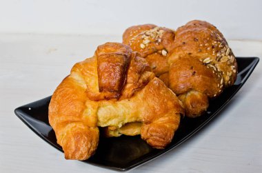 Mısır gevreği ve tereyağı kruvasan siyah tepsi ve ağartılmış ahşap masa ile mükemmel sağlıklı kahvaltı