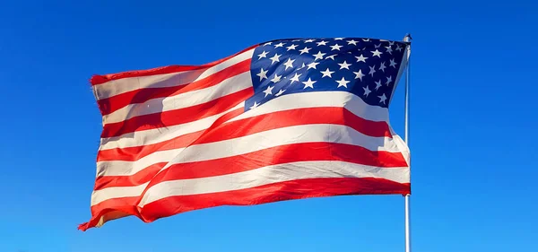 on Thanksgiving Day the flag of the United States of America flies with the wind of freedom in the blue sky and defends all American citizens