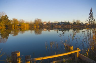 bitki örtüsü, gökyüzü ve batan güneşin mavi suda yansıyan kıyıya huzurlu lake