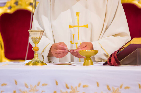 hand of the pope with consecrated host that becomes the body of jesus christ and chalice for wine, blood of christ, in the churches of rome and all over the world