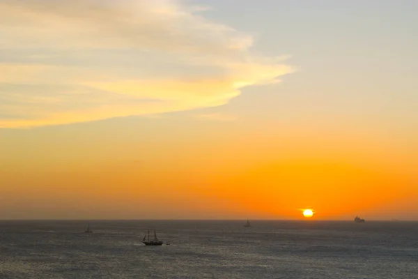 Orange sun over the water. In the sky orange clouds and small yachts in the ocean, Aruba, over the ocean, the sun sets over the horizon,  August 2014
