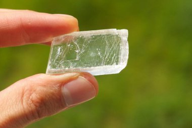 Iceland spar, a colorless and transparent mineral crystal held in a hand