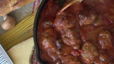Domates soslu spagetti ve köfte dökme demir tavada pişiyor.