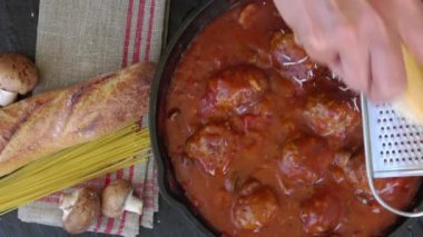 Domates soslu parmesan peynirli spagetti ve köfte dökme demir tavada pişiyor.