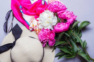 Siyah kurdeleli hasır şapka, beyaz ve fuşya çiçekli buket, ipek atkı ve leylak arka planda izole edilmiş güneş gözlüğü. Düz yat, kapat.. 