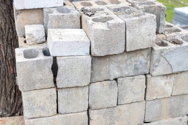 Ağacın yakınındaki kullanılmış ve hasarlı gri tuğla yığını. İnşaat fikri kavramı 