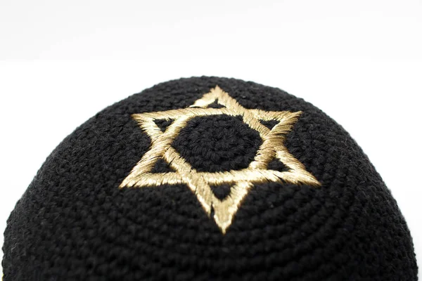 Beyaz arka planda altın renkli bir David yıldızıyla siyah bir kippah 'ın yakın çekimi..
