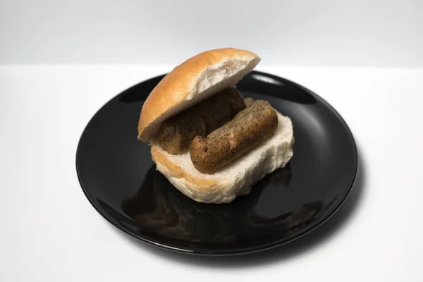 Siyah bir tabakta beyaz bir arka planı olan bir broodje frikandel. Hollanda usulü frikandel.. 