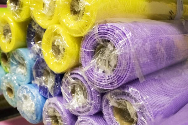 Warehouse packaging materials. Rolls of decorative wrapping paper of different colors are on the store shelf.