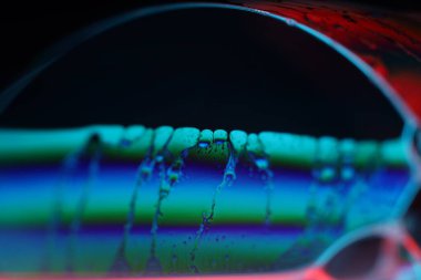 Siyah arkaplanda parlak çok renkli sıvı yüzey, parazit deseni