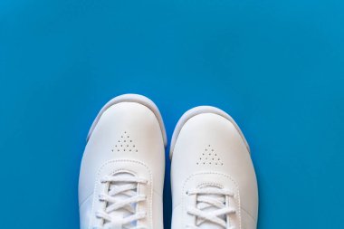 Mavi arka planda beyaz spor ayakkabılar. İçerik fotoğrafı. Spor ayakkabılar.